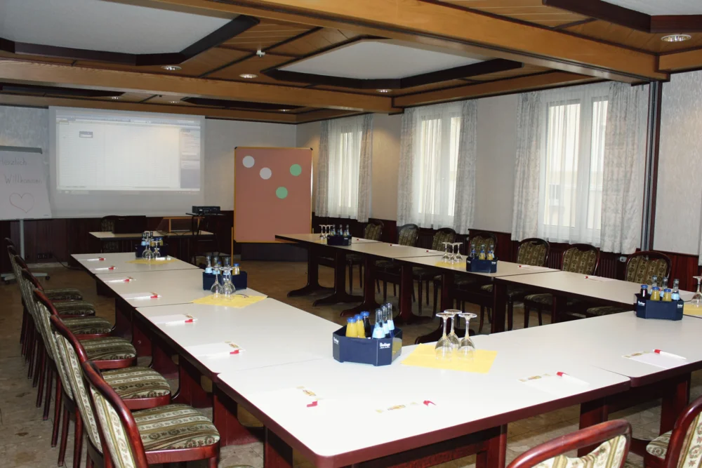 Konferenzraum mit Tischen, Stühlen, Projektor und Getränken