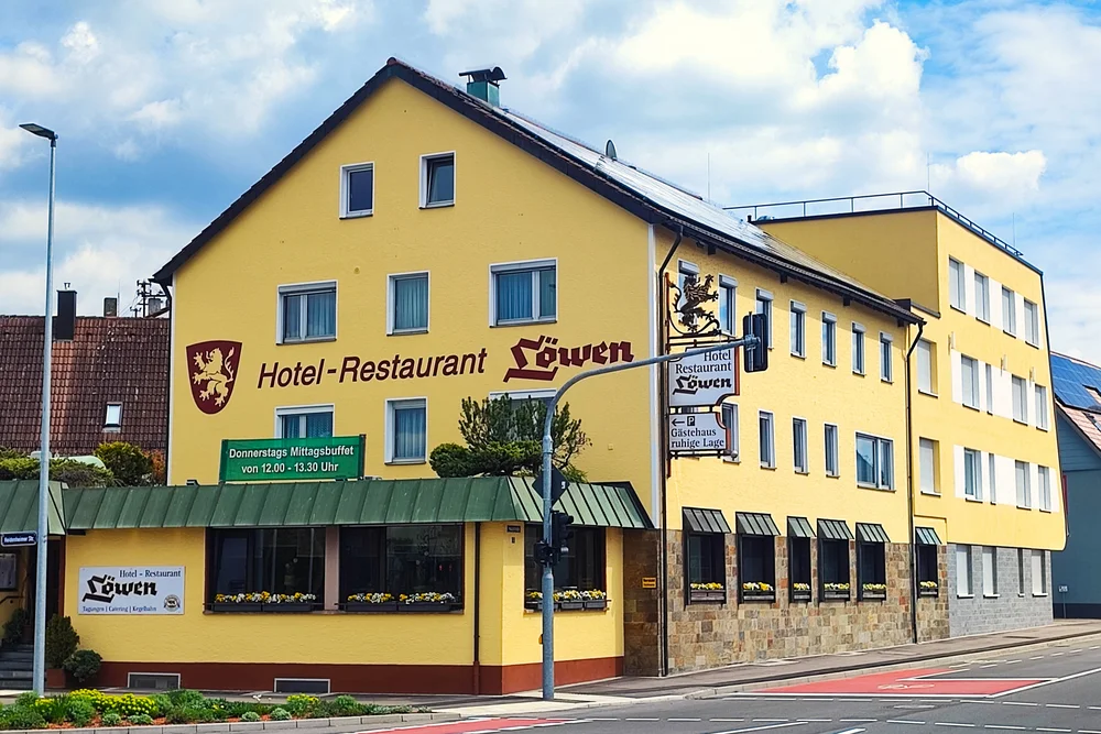 Gelbes Hotel-Restaurant Löwen an Straßenecke bei bewölktem Himmel