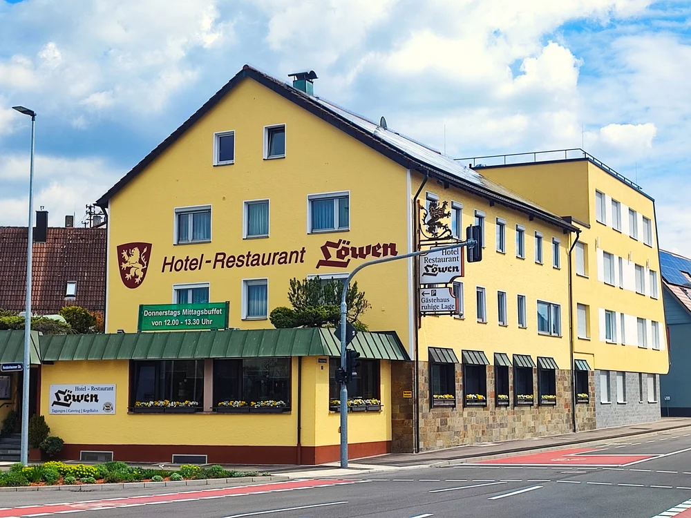 Gelbes Hotel-Restaurant Löwen an Straßenecke bei bewölktem Himmel