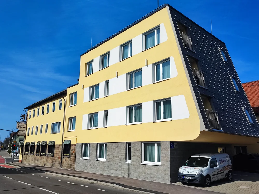 Gelbes Hotelgebäude mit weißen Fenstern und blauem Himmel