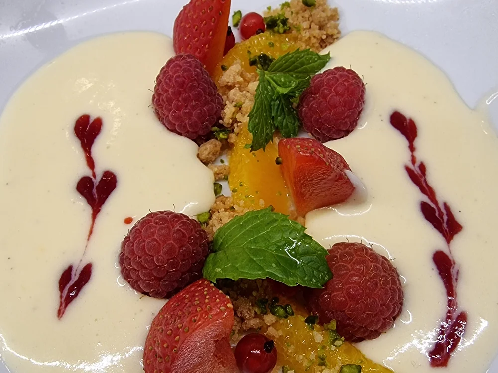 Dessert mit Vanillesauce, Himbeeren, Erdbeeren, Minze und Keksbröseln